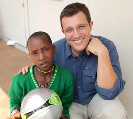 Young child holding a soccer ball next to a man.