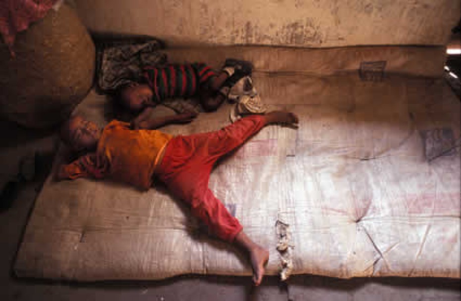 two small children sleeping on mat on floor