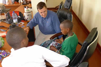 Two young children with a man in a classroom.