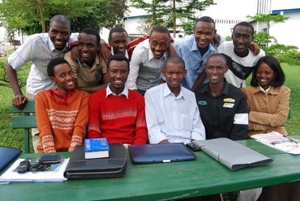 group of smiling young people behind a green table
