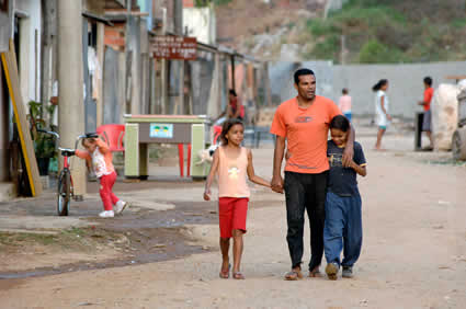 man walking down dirt road with arm around boy and holding the hand of a girl