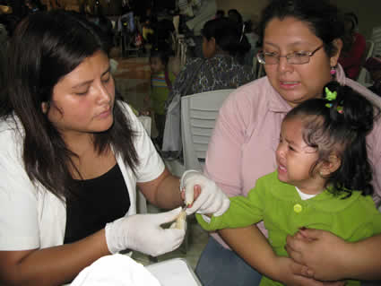 woman wearing rubber gloves working with woman and small girl
