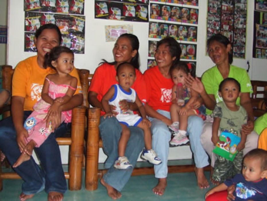 smiling women holding babies and young children