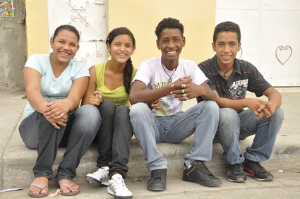 two girls and two boys sitting on the sidewalk