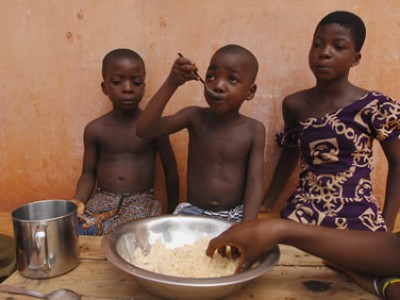 three children eating from large bowl