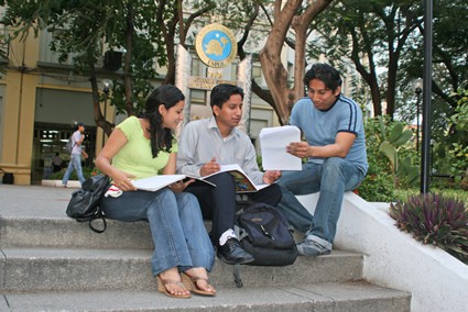 three young people sitting on steps reading notebooks