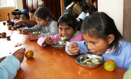 children sitting at a table eating a meal