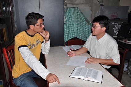 two people sitting at a table discussing a Bible lesson