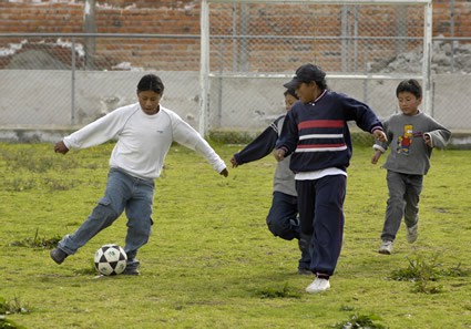 four children outside playing soccer