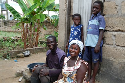 man and woman with two children outside home