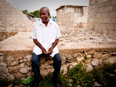 Haitian man sitting near damaged building