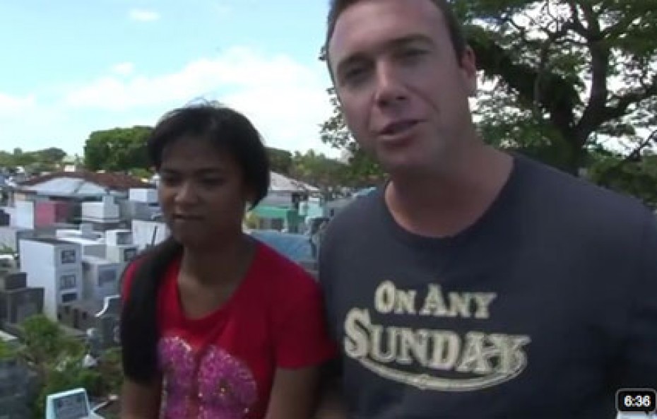 A man in a blue shirt with a girl in a red shirt and a tree in the background