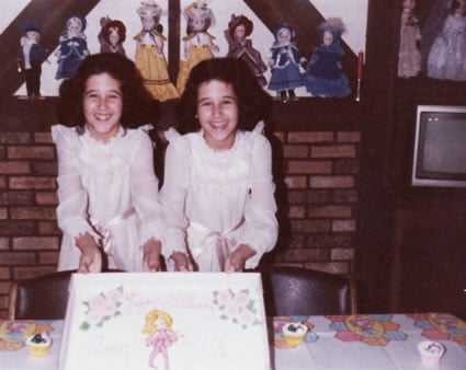older twin girls celebrating birthday with cake