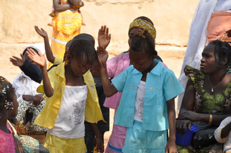 children with heads bowed and hands raised