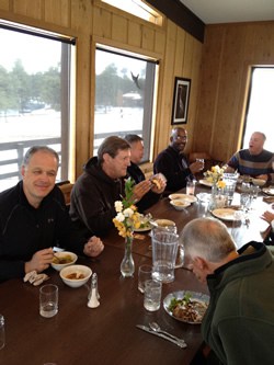 a group of men sitting at a table having lunch