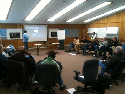 group of people in a meeting with a person at a screen