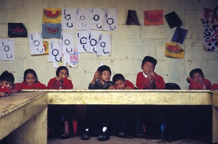 Young children sitting at a table in a classroom.