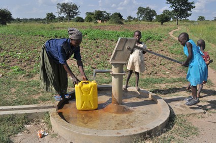 Woman filling a water container with the help of children.