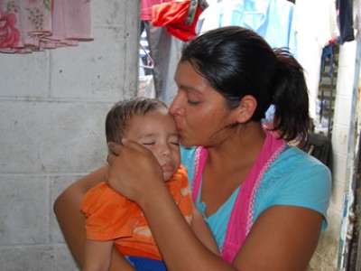 A woman kissing a baby on the forehead