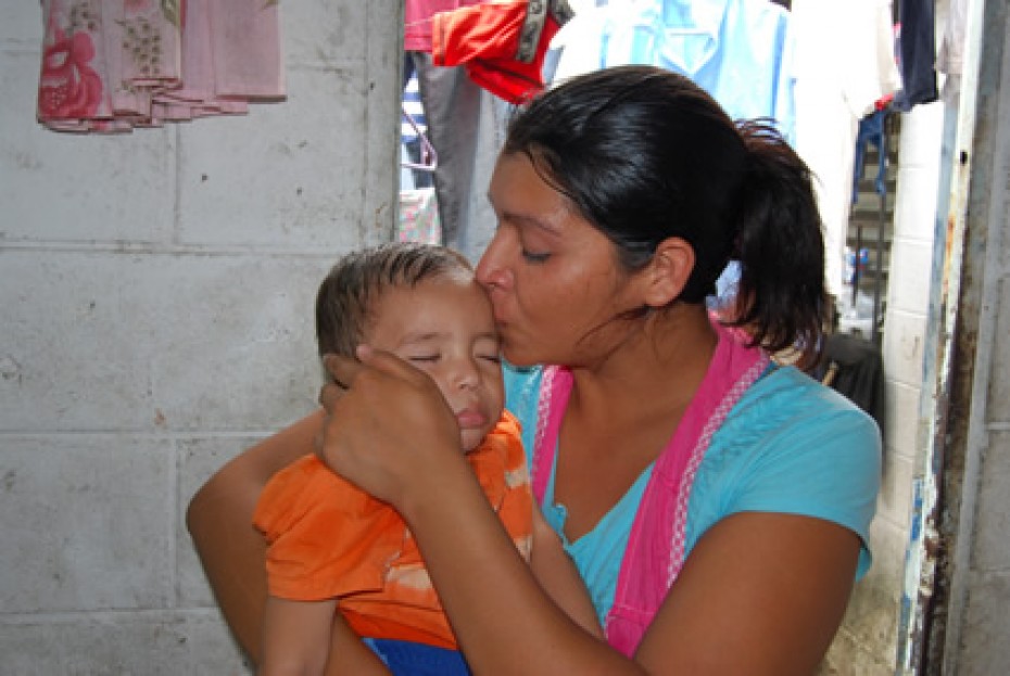 A woman kissing a baby on the forehead