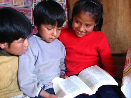 two boys and a girl looking at a book