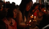 group of young girls in low lighting holding candles during a worship service