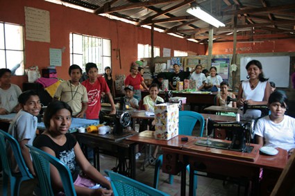 Large classroom with students and sewing machines.