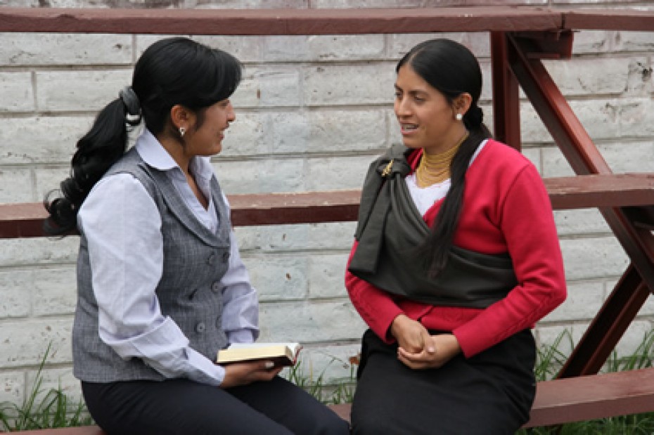 two women sitting on bench talking to each other