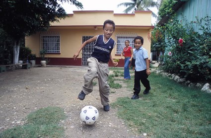 Three young children playing with a soccer ball.