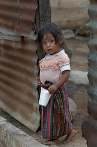 Toddler standing next to a metal building.