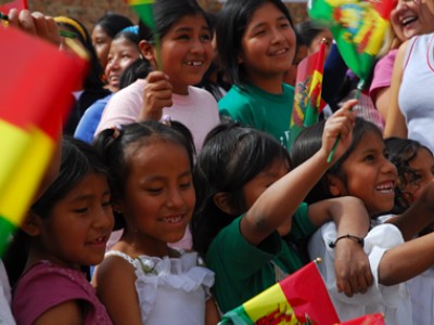 smiling children waving Bolivian flags