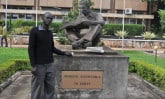 young man standing next to statue