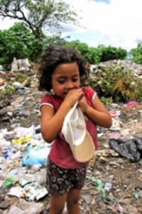 girl standing in dump holding a hat