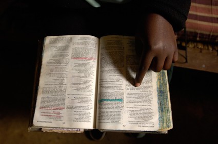 person pointing to a scripture in the Bible