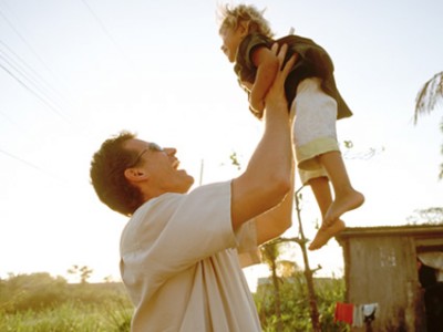 smiling man lifting a child up in the air