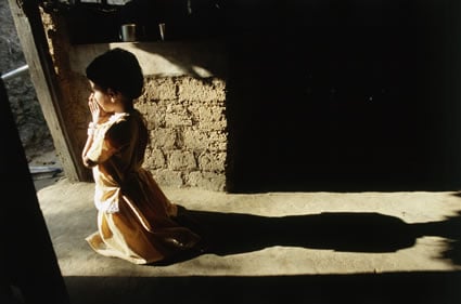 small girl praying in a doorway