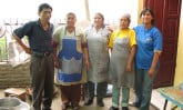 five people standing a kitchen