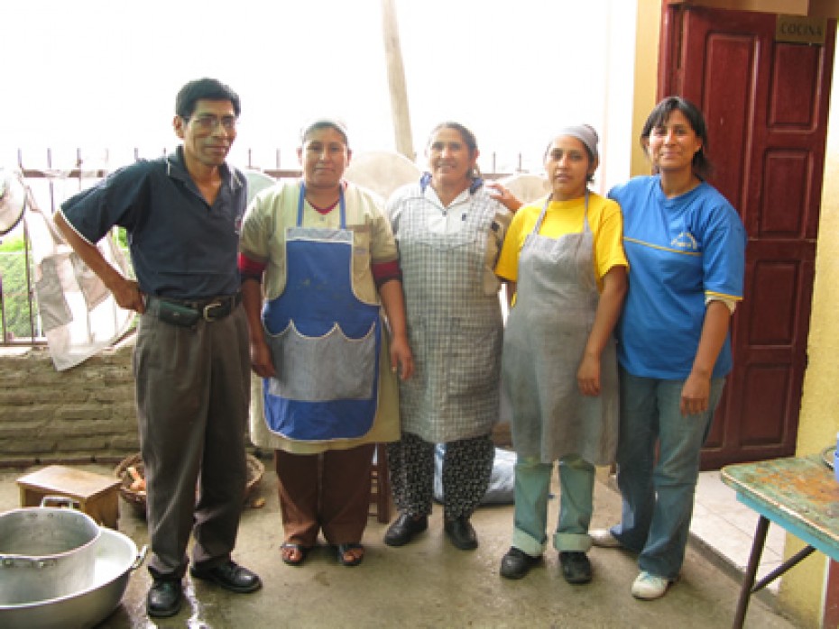 five people standing a kitchen