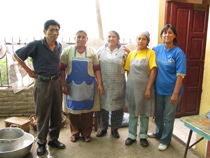 five adults standing inside a kitchen
