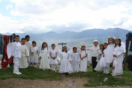 Children standing outside by a cross.