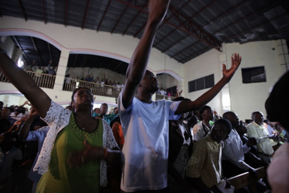 people in church worshiping with arms raised