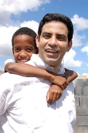 smiling man in white shirt with boy hugging his neck