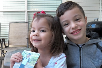 boy and girl smiling while holding a picture of their sponsored child