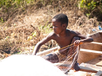 Young boy in a boat with a fishing net.