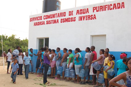 line of people outside of a water purification facility waiting to fill water jugs