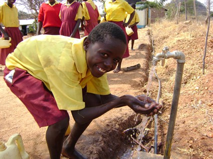 young boy laughing as he washes hands