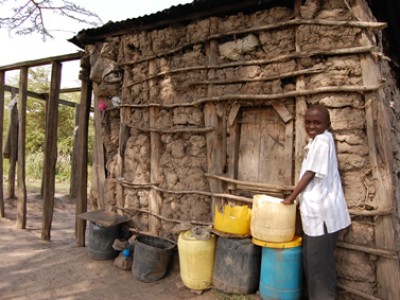 girl standing outside of home made of mud