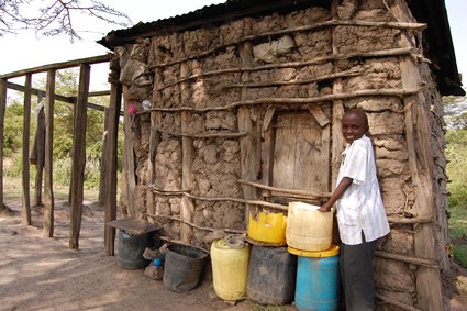 young girl standing outside house made of mud