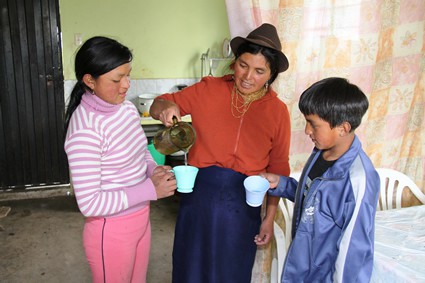 woman pouring water for a girl and a boy