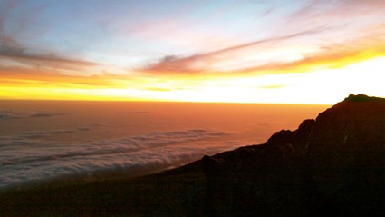 Sunrise and clouds over a small mountain.